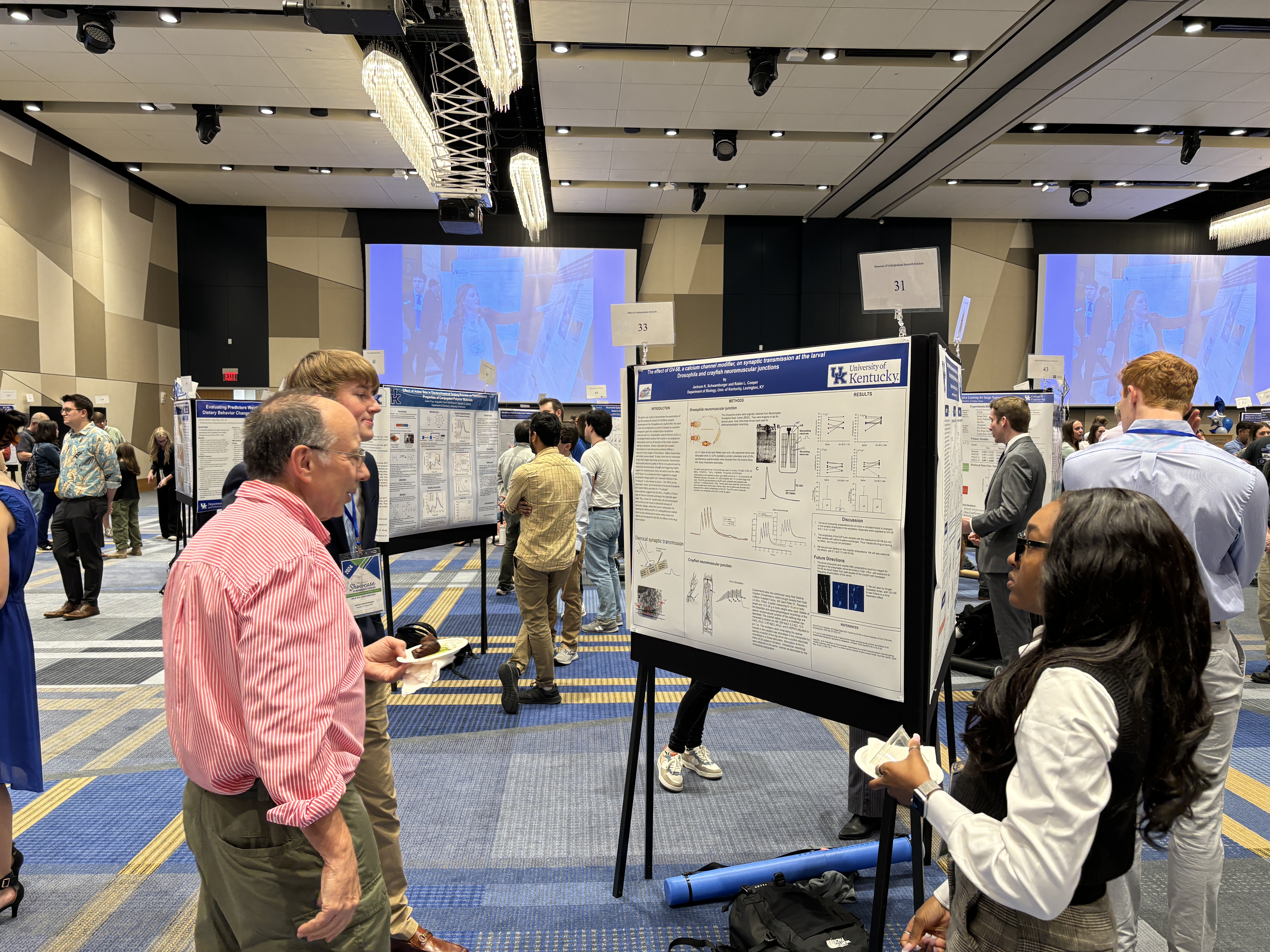 faculty standing with students at poster presentation