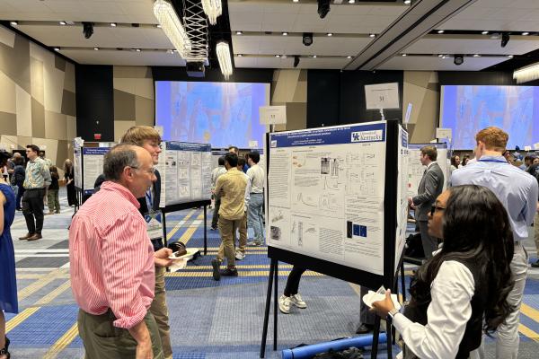 faculty standing with students at poster presentation