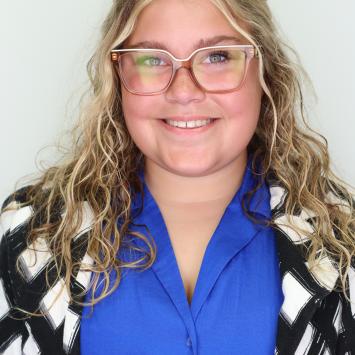 Professional picture of student worker smiling in a blue dress shirt with a black and white blazer