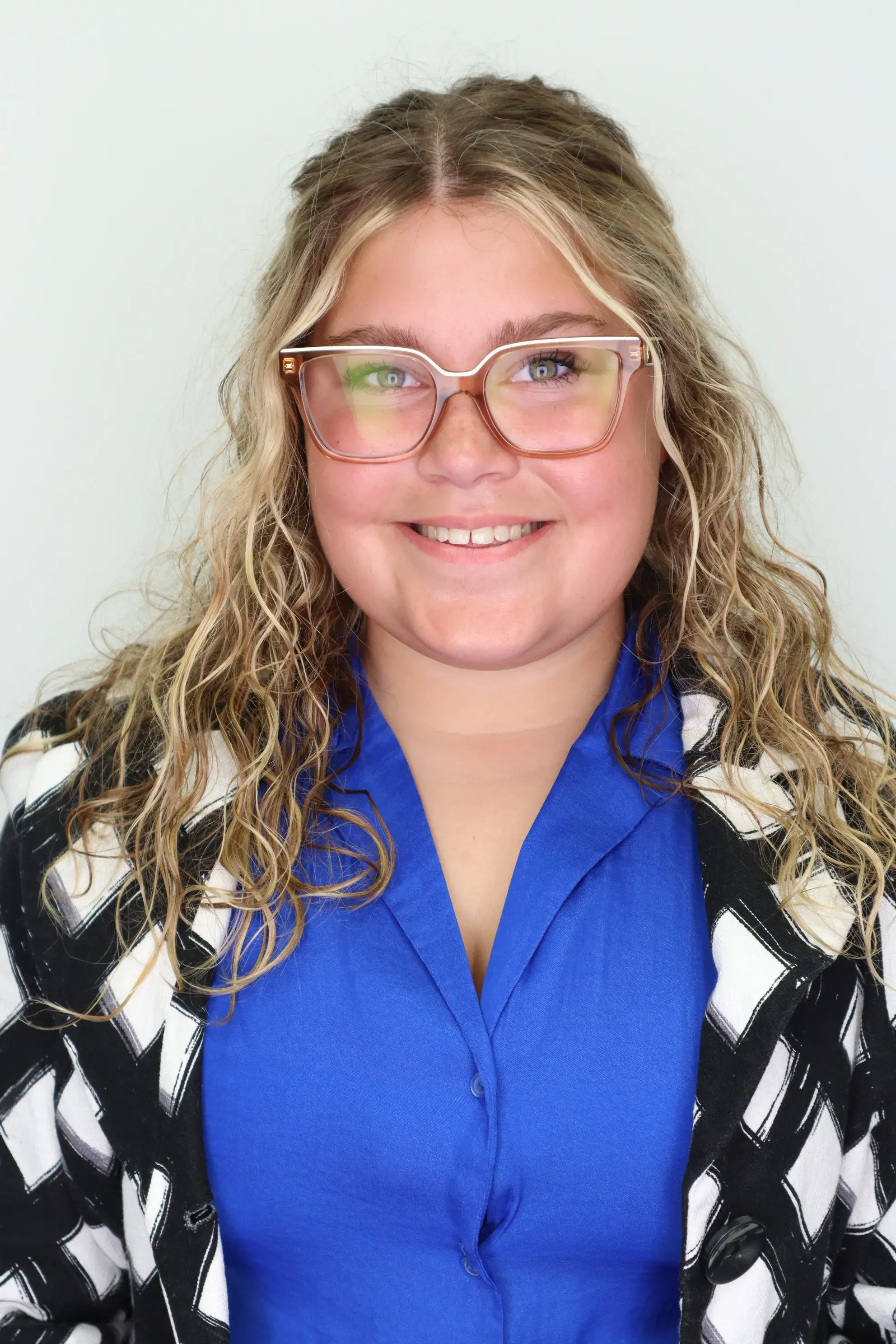Professional picture of student worker smiling in a blue dress shirt with a black and white blazer